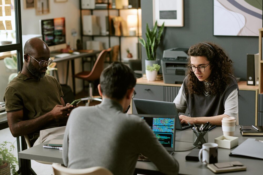 Multiethnic coworkers collaborating on laptops in modern office
